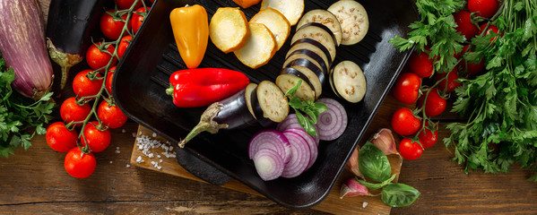 Raw vegetables for cooking on a grill pan on a wooden background top view