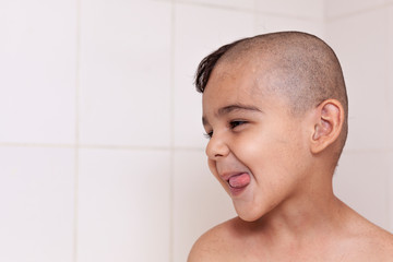 Six-year boy at haircutting at home. Father cut half of the son's hair off at the bathroom