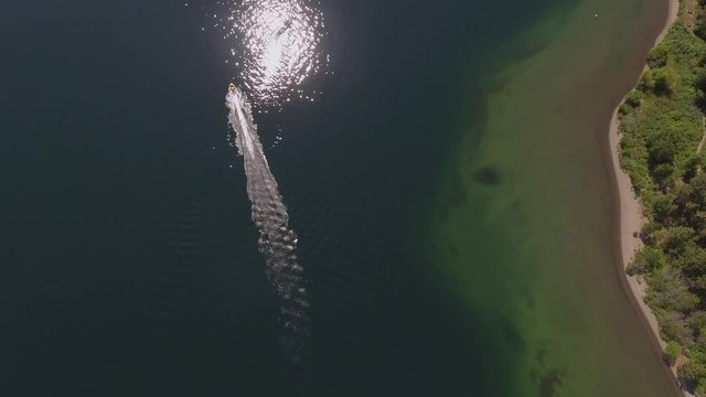 Rotating aerial of a motorboat with a long wake and reflected sunball