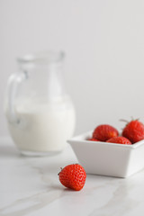 Close-up view of strawberry. Jar of cream on background.