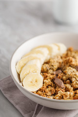 Breakfast with granola with banana. Pieces of chocolate and jar of granola on background.