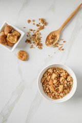 Two wooden bowls of granola on white marble table