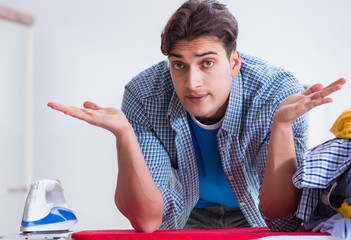 Young man husband doing clothing ironing at home