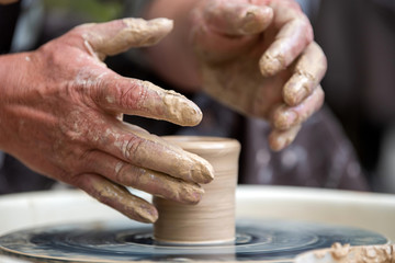 Potter makes pottery dishes on potter's wheel