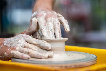 Potter makes pottery dishes on potter's wheel