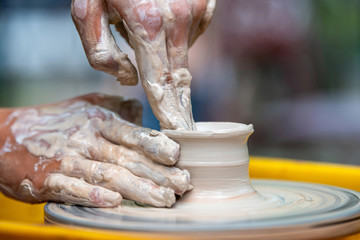 Potter makes pottery dishes on potter's wheel