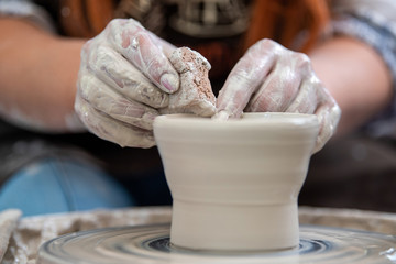 Potter makes pottery dishes on potter's wheel