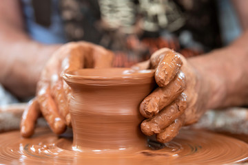 Potter makes pottery dishes on potter's wheel