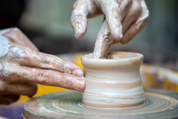 Potter makes pottery dishes on potter's wheel