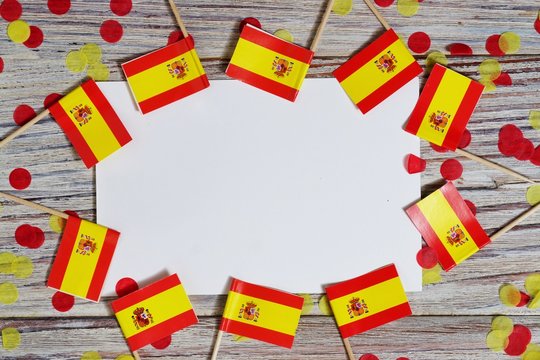 October 12. Independence day Spain, the concept of independence , patriotism and freedom. Mini paper flags with yellow red confetti and white postcard on wooden background