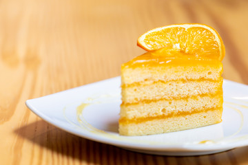 Orange cake with orange topping  on wooden table in coffee cafe