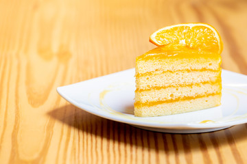 Orange cake with orange topping  on wooden table in coffee cafe