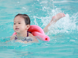 Fototapeta na wymiar Mother teaching kid in swimming pool with foam noodle