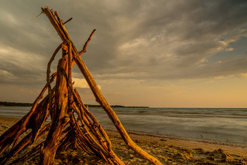 sunset at Sandbanks Beach Picton Ontario Canada with nice sun, clouds, branches, lake view, sand, and light.