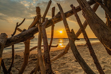sunset at Sandbanks Beach Picton Ontario Canada with nice sun, clouds, branches, lake view, sand, and light.