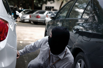 Masked robber in a balaclava ready for stealing automobile car. Robbery and crime concept.