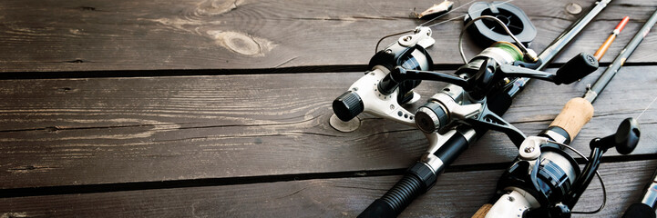 Fishing rods and reels on wooden background with text space