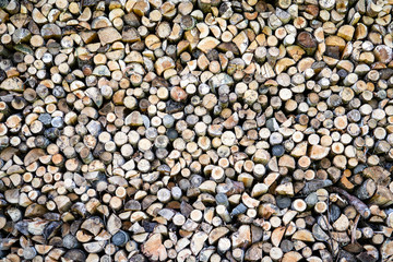 Background of dry chopped firewood logs in a pile. Preparation for the winter season, fossil fuels