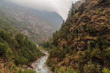 Dudh Koshi snow river (or Dudh Kosi river) flows in mountain valley near Phakding village in Himalayas in Nepal. Nature, Lakes and Rivers, Mountains, Travel and Tourism concept. - obrazy, fototapety, plakaty