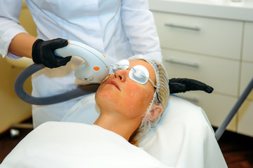 Doctor in medical gloves applies the patient special gel. Anti acne phototherapy with professional...