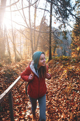 woman hiker with backpack wearing in red jacket is walking through a foggy autumn woods at the...