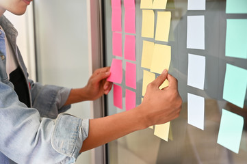 Man using sticky note paper on windows office notice memo reminder.