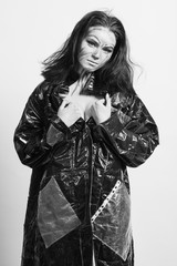 Model in a black raincoat made of cellophane and in creative make-up