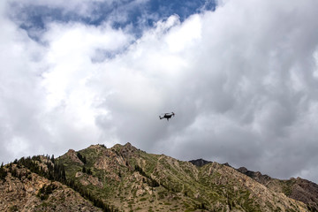 Drone in the cloudy sky over a mountain range. Traveling in Kyrgyzstan