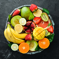 Fruits in a wooden box. Citrus, melon, pomegranate, strawberry, banana. Top view. Free space for your text.