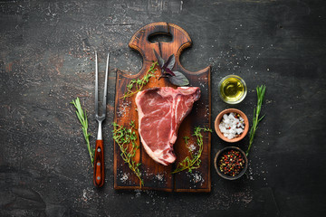 Raw T-bone steak on a wooden table. Top view. Free space for text.
