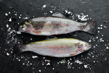 Raw fish trout on a black background. Top view. Free space for your text.