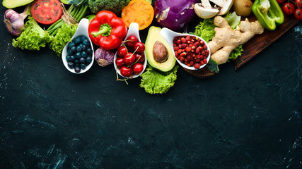 Fresh vegetables and fruits on a black background. Vitamins and minerals. Top view. Free space for...