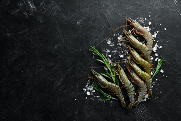 Raw black tiger prawns with lemon. Seafood. Top view. On a black background. Free copy space.