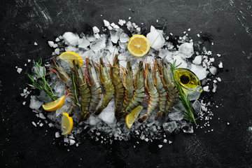black tiger prawns with lemon on ice. Seafood. Top view. On a black background. Free copy space.