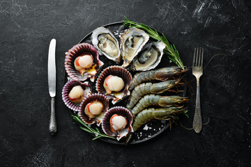 Seafood. Oysters, scallops, shrimp. Top view. On a black background. Free copy space.