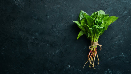 Fresh green spinach on a black stone table. Top view. Free space for your text.