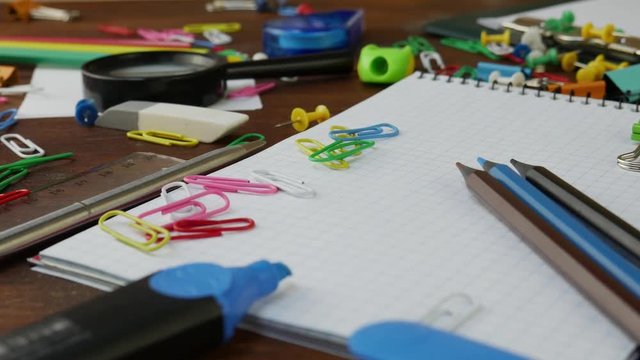 Multicolored Pencils, Paper Clips and Notebook on Brown Wooden Desk. School Office Supplies on brown wooden table. Concept of back to school