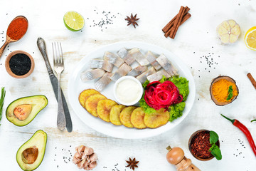 Herring with baked potatoes. In the plate. On a wooden background. Top view. Free space for your text.