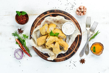 Fried fish fillet with sauce. On a wooden board. On a wooden background. Top view. Free space for your text.