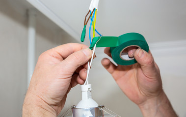 Man is holding adhesive tape in his hands.  Electrical insulator for light bulb. Maintenance repair...