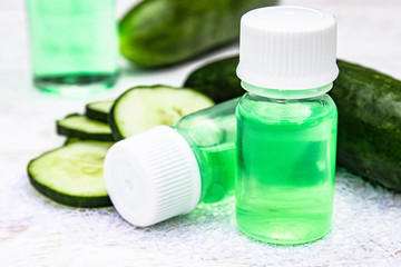 Sliced cucumber and a bottle of cucumber extract. Liquid cosmetics for skin care.