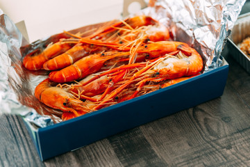 Top view of Thai grilled prawns (shrimps) in the shell in paper box that wrap with foil paper.