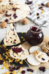 Salty crackers with sweet cranberry cheese served with walnut, raisin, dried cranberry and jam