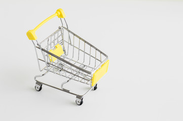 Small shopping cart toy on white background. Empty shopping trolley