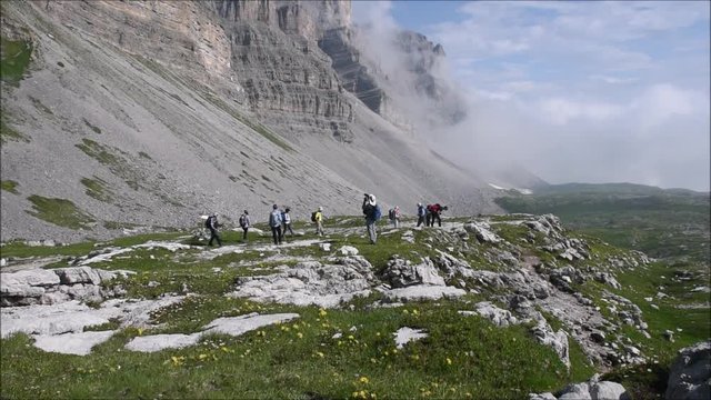 Senior hikers under the Groste massif. Rocky landscape of Brenta Dolomites in Italy