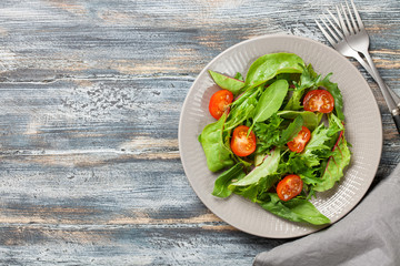 Vegetables salad in a plate on a wooden background.  Top view