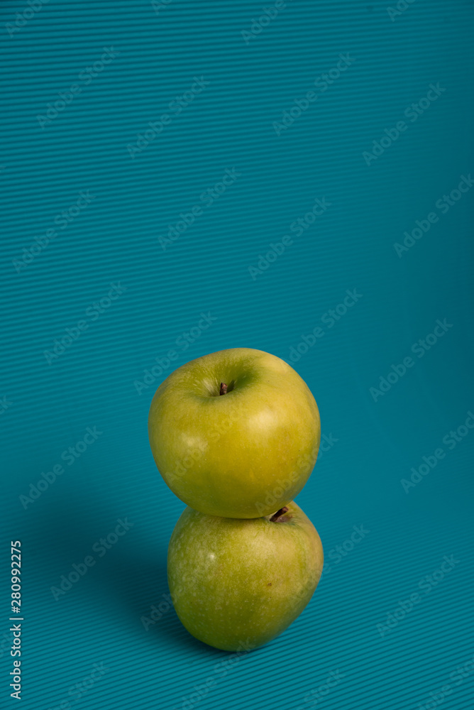 Wall mural two green apples on a light blue background.