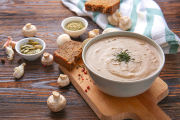 Bowl of tasty mushroom cream soup on wooden table