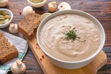 Bowl of tasty mushroom cream soup on wooden table