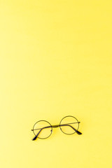 Fashionable eyeglasses on yellow background with copyspace